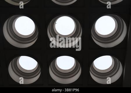 Vue d'un plafond architectural qui utilise des ouvertures circulaires, construites avec du béton, offrant un aperçu du ciel visible à travers ces sh uniques Banque D'Images