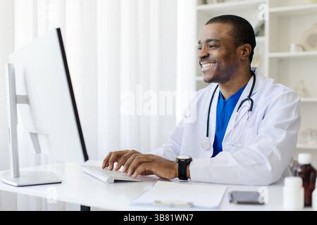 Sourire beau assis au bureau dans le bureau Banque D'Images