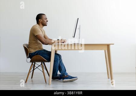 Homme afro-américain assis au bureau et travaillant sur ordinateur Banque D'Images