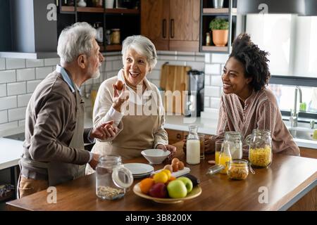 Famille multiethnique heureuse avec des parents âgés s'amusant et parlant dans la cuisine. Banque D'Images