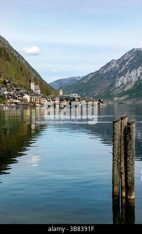 Vue panoramique sur le village de Hallstatt avec des maisons traditionnelles et des tours d'église reflétées dans les eaux calmes du lac entouré par les montagnes majestueuses des Alpes à Aust Banque D'Images