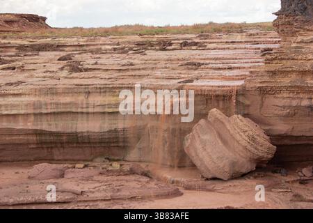 L'eau coule doucement sur des formations rocheuses stratifiées dans un paysage naturel serein. La lumière du soleil éclaire les surfaces lisses tandis que la verdure délimite le SC Banque D'Images
