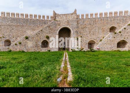 Mur historique de la forteresse en pierre avec porte voûtée et paysage d'herbe verte Banque D'Images