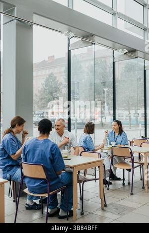 Professionnels de santé masculins et féminins prenant le petit déjeuner à la cafétéria du bâtiment de l'hôpital Banque D'Images