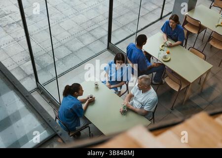 Vue en angle élevé des médecins hommes et femmes passant le temps de pause à boire un café dans la cafétéria à la clinique Banque D'Images