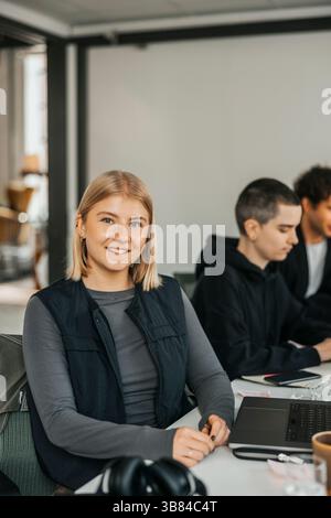 Portrait de jeune femme d'affaires souriante avec des cheveux blonds assis à table dans le bureau Banque D'Images