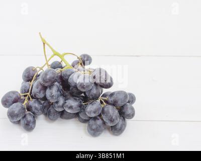 Les raisins de pourpre bouquet sur table en bois blanc avec copyspace Banque D'Images