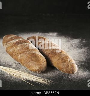 Deux faits maison pain de seigle entier avec du pain de farine de sarrasin sur fond texturé noir. Copier l'espace. Touche Bas Banque D'Images