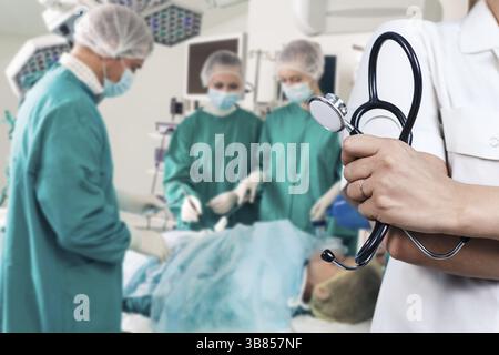 Médecin tenant un stéthoscope au-dessus de l'équipe des chirurgiens pendant une intervention chirurgicale Banque D'Images