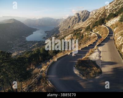 Mariés et mariés marchent le long d'une route asphaltée de haute montagne au-dessus de la baie. Banque D'Images