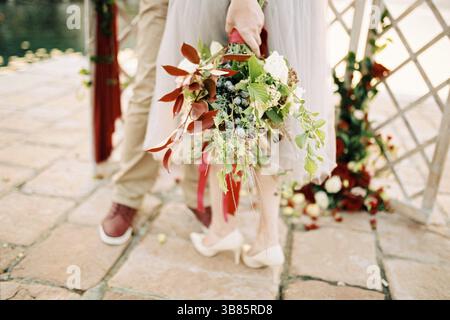 Bouquet de fleurs attaché avec un ruban dans la main de la mariée. Rogné. Banque D'Images