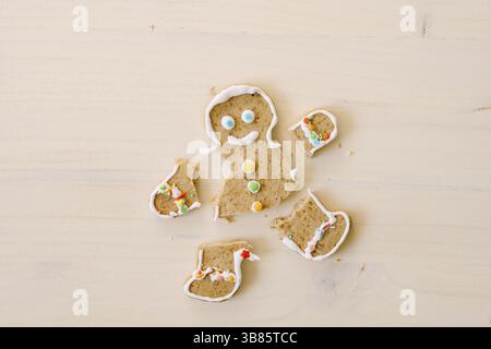 Homme de pain d'épice avec jambes et bras coupés. Les membres du cookie sont séparés du corps. Pain d'épice de Noël sur fond de bois blanc. Banque D'Images
