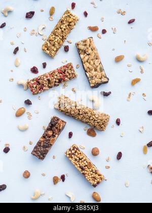 Barre de granola sur fond bleu. Ensemble de différentes barres de granola sur table en marbre blanc. DOF peu profond. Vue de dessus ou pose à plat. Vertical Banque D'Images