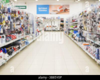 Résumé de l'allée de supermarché floue avec des étagères et des articles ménagers de base clients méconnaissable Banque D'Images