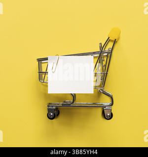 Liste de notes de panier et de papier blanc sur fond jaune. Concept shopping sur fond jaune vif. Note de papier blanc vide sur la voiture de magasinage Banque D'Images