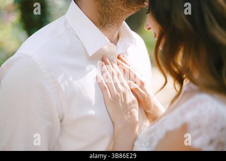 Le marié embrasse doucement la mariée sur le front, la mariée met ses mains sur la poitrine du marié. Banque D'Images