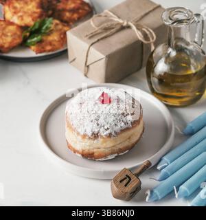Fête juive Hanukkah concept et arrière-plan. Hanukkah beignets alimentaires et crêpes de pommes de terre latkes, huile, boîte-cadeau, bougie et spinnig dre traditionnel Banque D'Images