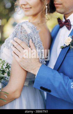 Kotor, Montenegro - 08.06.17: Marié dans un costume bleu hale la mariée avec un bouquet de fleurs par les épaules.Gros plan Banque D'Images