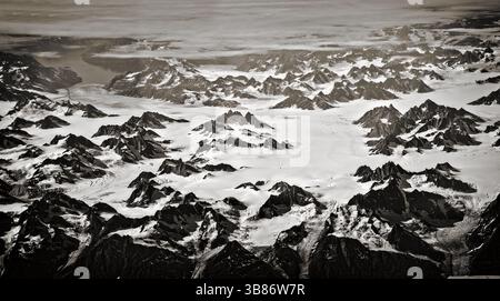 Vue aérienne du paysage du Groenland, les montagnes sont couvertes de neige. Côte ouest du Groenland. Vue en avion des sommets montagneux. Image en noir et blanc de Banque D'Images