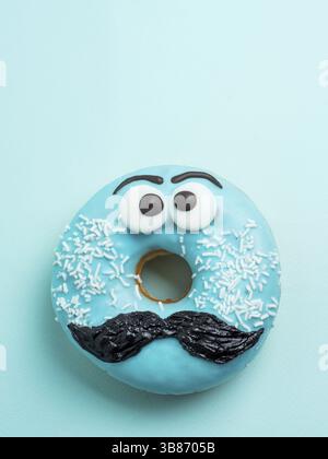 Beignet glacé bleu avec moustache. Donut bleu avec drôle de visage avec moustache sur fond bleu. L'espace de copie pour le texte. La masculinité ou le jour de père concep Banque D'Images