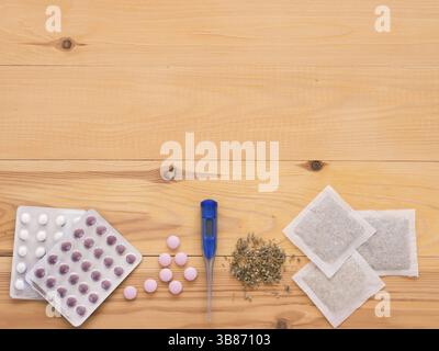 Comprimés, gouttes, herbes et thermomètre sur un fond en bois clair avec espace de copie. Phytothérapie VS médecine chimique la voiture saine alternative Banque D'Images