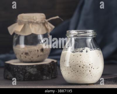 Levain de levain de blé et de seigle actif dans un bocal en verre sur fond de bois brun. Démarreur pour pain au levain. Image tonifiée. Copier l'espace Banque D'Images
