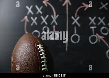 Ballon de football américain contre le schéma de jeu flou, gros plan Banque D'Images