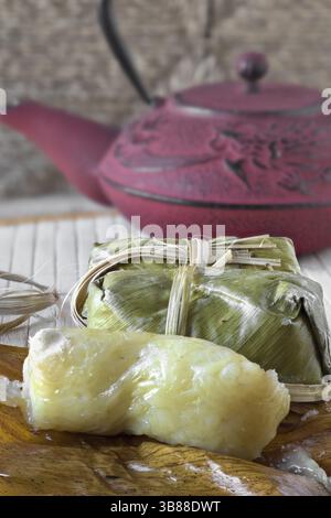 Gâteau de riz collant avec taro dans des feuilles de banane. Théière en arrière-plan Banque D'Images