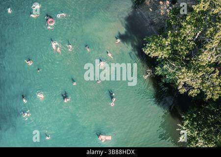 Drone aérien vue de haut en bas de personnes méconnaissables nageant dans le lac. Belle eau bleue avec beaucoup de gens se reposer sur la plage, nager et sauter à pon Banque D'Images