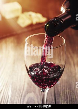 Libre de vin rouge verser dans le verre sur la table en bois. heese sur arrière-plan. Copier l'espace. Effet Sunflare Banque D'Images