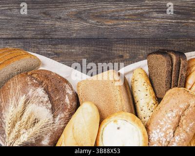 Assortiment différents types de pain. Pain de style rustique sur une table en bois brun. Vue de dessus ou pose à plat. Copier l'espace Banque D'Images