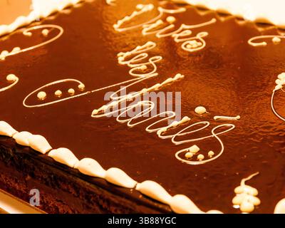Gros plan d'un gâteau de mariage glacé au chocolat avec « vive les mariés » écrit sur le dessus, célébrant un mariage à la française. Banque D'Images