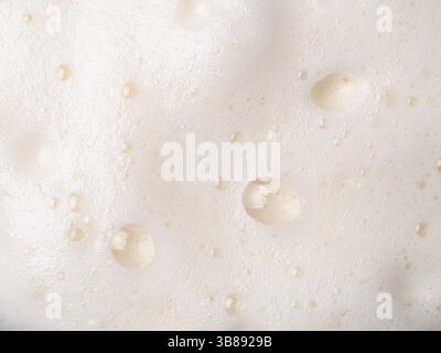 Texture de mousse extrême en gros plan comme arrière-plan. Bière ou mousse cappucino avec bulles macro shoot. Copier l'espace pour le texte Banque D'Images