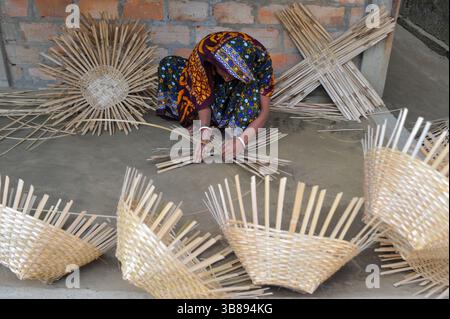 23 janvier 2024 : une femme tisse des produits fabriqués à partir de cannes de bambou à Haripur, dans le quartier de Nomshuddha à la périphérie de Sylhet, au Bangladesh. Ils vendent vingt paniers à des négociants locaux à un prix de gros de 600 TK. Depuis un siècle et demi, environ 60 familles de ce village sont impliquées dans le tissage de produits artisanaux en rotin pour générer des revenus supplémentaires pour leurs familles. Avec l'augmentation des produits ménagers en plastique qui prennent le dessus sur le marché, les artisans se retirent de plus en plus de l'industrie de la canne de bambou naturelle. Maintenant, certaines de ces personnes font encore peu de travail juste Banque D'Images