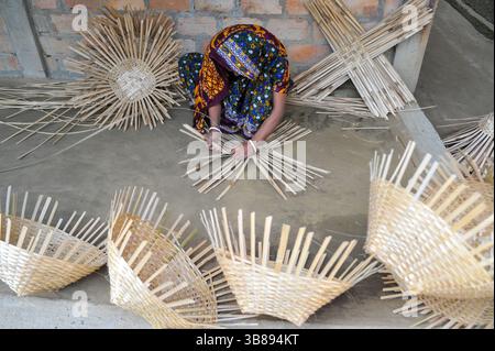 23 janvier 2024 : une femme tisse des produits fabriqués à partir de cannes de bambou à Haripur, dans le quartier de Nomshuddha à la périphérie de Sylhet, au Bangladesh. Ils vendent vingt paniers à des négociants locaux à un prix de gros de 600 TK. Depuis un siècle et demi, environ 60 familles de ce village sont impliquées dans le tissage de produits artisanaux en rotin pour générer des revenus supplémentaires pour leurs familles. Avec l'augmentation des produits ménagers en plastique qui prennent le dessus sur le marché, les artisans se retirent de plus en plus de l'industrie de la canne de bambou naturelle. Maintenant, certaines de ces personnes font encore peu de travail juste Banque D'Images