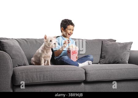 Garçon et un chien assis sur un canapé et mangeant du pop-corn isolé sur fond blanc Banque D'Images