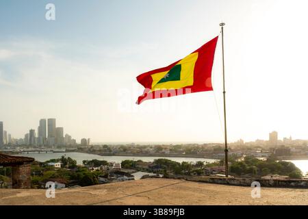 Pris du château de San Felipe à Carthagène, en Colombie, le drapeau de la ville flotte fièrement sur la skyline et la baie pendant la lumière dorée du coucher de soleil. Banque D'Images