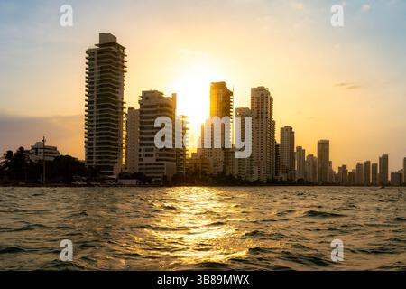Coucher de soleil sur l'horizon moderne de Carthagène, Colombie, vu de la mer avec des reflets brillants sur l'eau et le ciel chaud. Banque D'Images