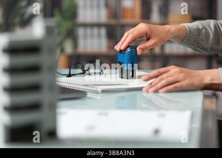 Main féminine met un timbre sur une affaire immobilière. Concept d'accords immobiliers Banque D'Images