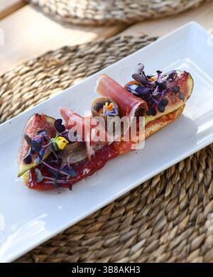 Bruschetta savoureuse au prosciutto et figues sur plaque blanche Banque D'Images