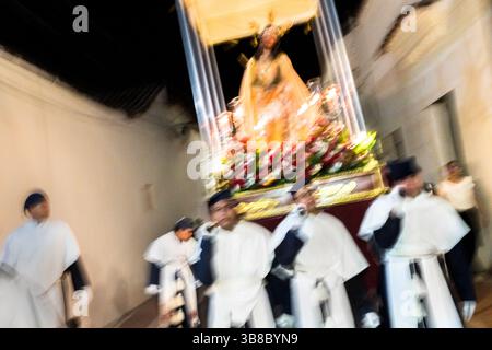 Nazarenos, membres pieux d'une confrérie religieuse, portent un char (paso) représentant la passion du Christ pendant la procession de la semaine Sainte à Mompox, en Colombie. Banque D'Images