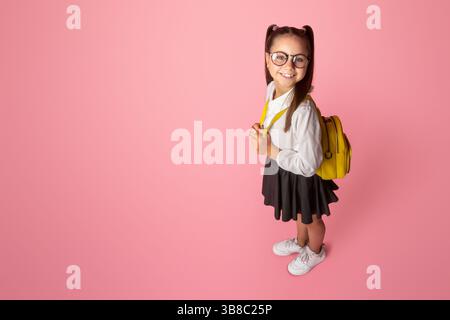 Drôle d'enfant, l'éducation précoce et la vie scolaire. Bonne fille en uniforme avec sac à dos Banque D'Images