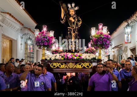 Les dévots catholiques, membres d'une confrérie religieuse, portent un char (paso) pendant la procession de la semaine Sainte à Mompox, en Colombie. Banque D'Images