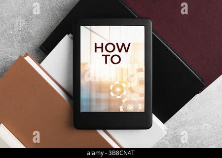 Comment documenter ouvrir dans le dispositif e-book et différents livres sur la table grise, vue de dessus. Guide de l'utilisateur Banque D'Images