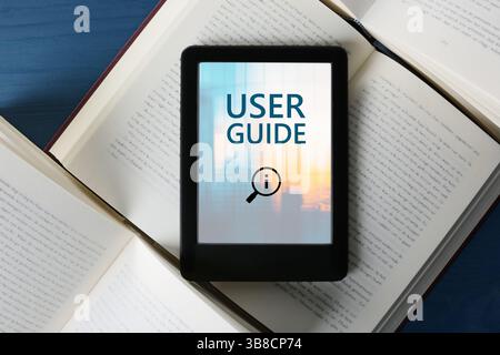 Guide de l'utilisateur document ouvert dans le dispositif e-book et différents livres sur la table en bois bleu, vue de dessus Banque D'Images