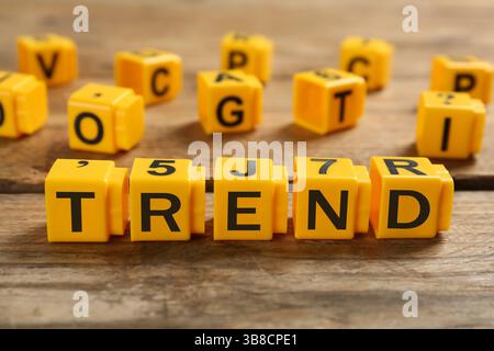 Mot tendance fait de cubes jaunes avec des lettres sur une table en bois Banque D'Images