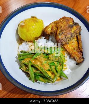 Repas indonésien d'ayam bakar ou de poulet grillé, de gulai telur ou d'oeuf à la coque dans un curry doux et un buncis ou de longs haricots verts tranchés. Banque D'Images