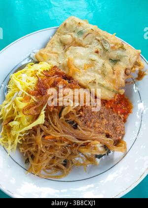 Cuisine indonésienne - Nasi uduk avec bihun goreng ou vermicelles frits, rendang sapi, tempe mendoan et omelette râpée. Banque D'Images