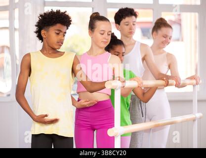 Adolescent afro-américain maîtrisant la première position à barre dans un studio de ballet Banque D'Images