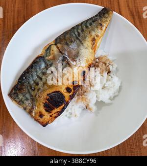 Maquereau grillé ou Ikan Kembung servi avec du riz blanc cuit à la vapeur avec de la sauce soja douce kecap manis servie dans une assiette blanche. Banque D'Images